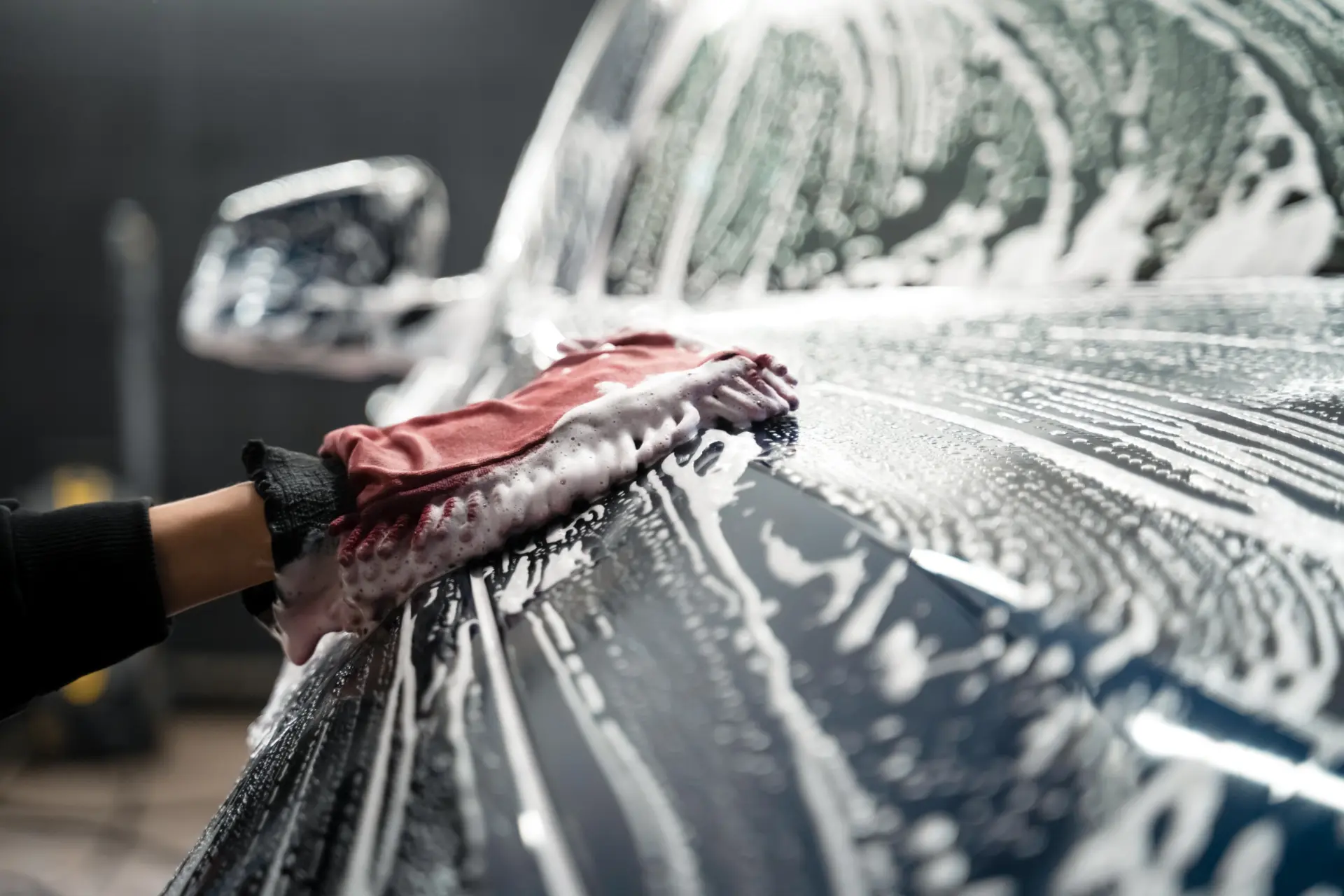 Hand washing a car covered in thick foam