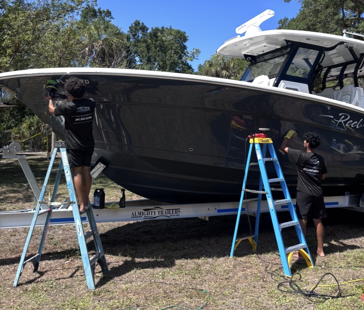 Dean and Jonah polishing a large boat on a trailer